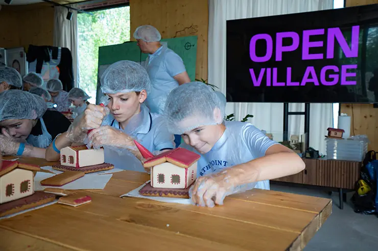 Дети строят пряничные домики с окнами на выставке Open Village 2024