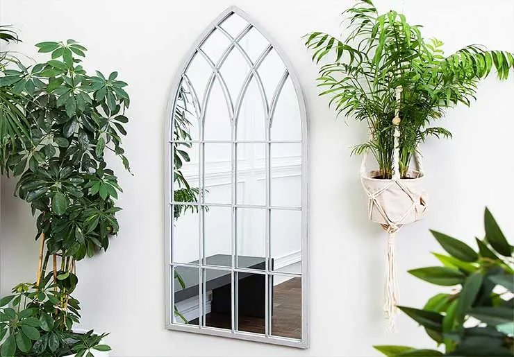 Зеркала и комнатные растения отлично дополняют гостиную с большими окнами